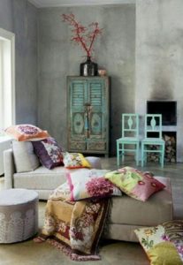 Kékre festett szekrény és székek, színes párnák egy kanapén